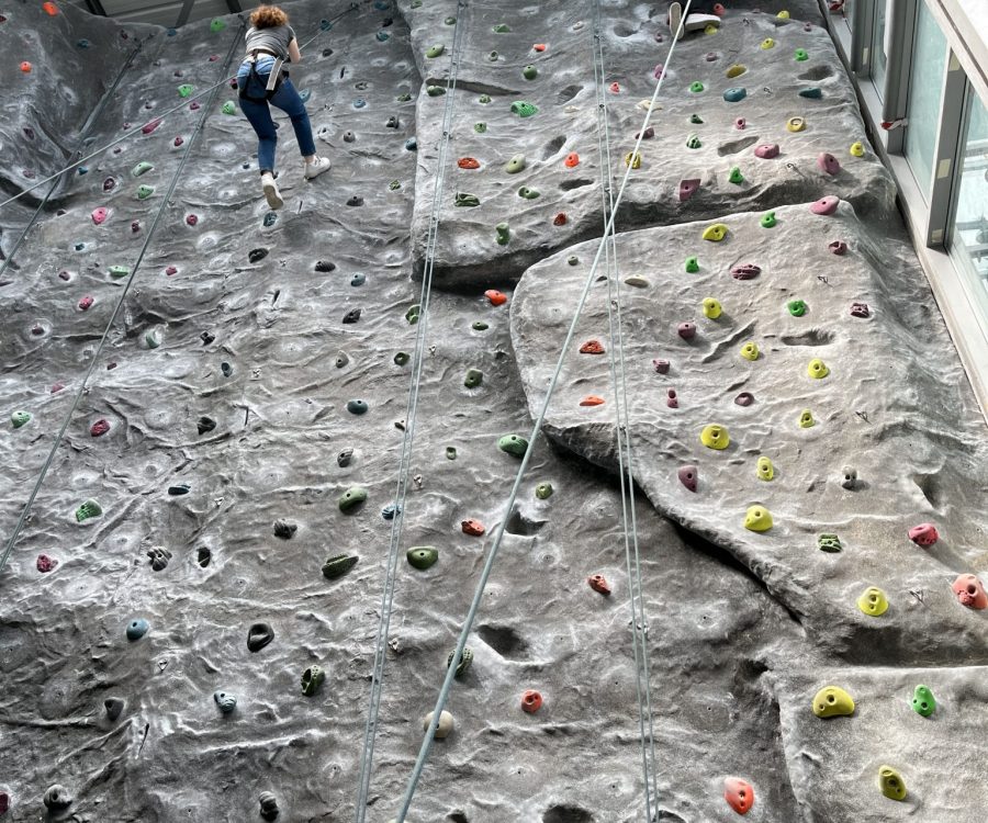 A girl abseils down from the top of the climbing wall