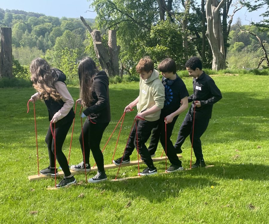 5 young people manoeuvring a giant pair of skis